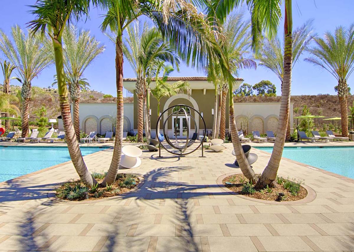 Two pools separated by a metal art piece and palm trees.